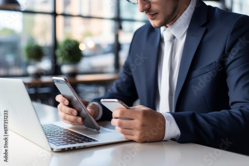An analyst businessman holding a smartphone in both hands and operating a keyboard. Chatting and website search on the internet at a white table in a cafe. Online meeting. Business and global network 