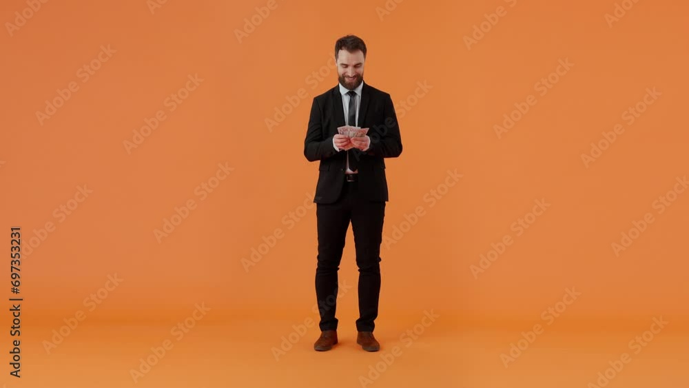 Happy business man counting stack of dollar bills standing against bright wall Happy business man counting stack of dollar bills standing against bright wall