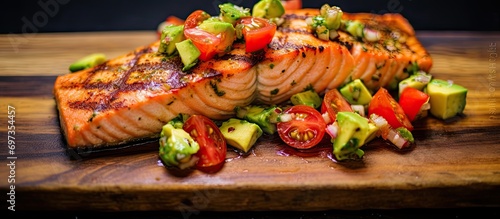 Tasty and nutritious grilled salmon with avocado and tomato salsa. photo