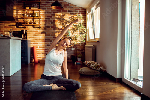 Relaxed woman doing a side stretch during a yoga session in her sunny home
