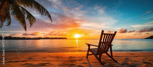 Beach chair with palm tree and sea at sunrise - vacation concept.