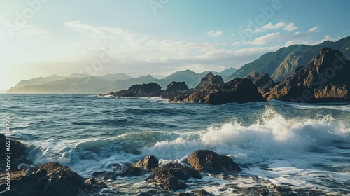 A shot that captures the beauty of a sea and rocky mountain in the distance with clouds in the sky.