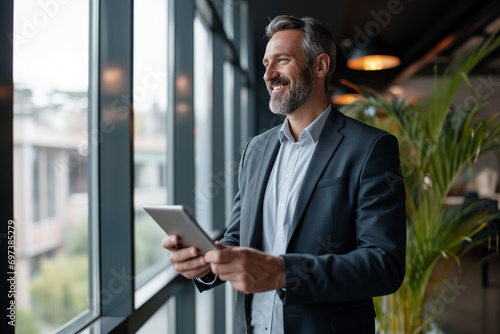 Smiling Middle-Aged Businessman Using Tablet in Office