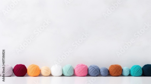  a row of multicolored balls of yarn lined up in a row in front of a plain white wall. photo