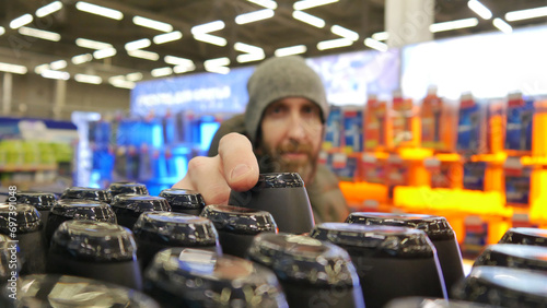 Close-up of many black plastic bottles of shampoo or shower gel and a male buyer taking one