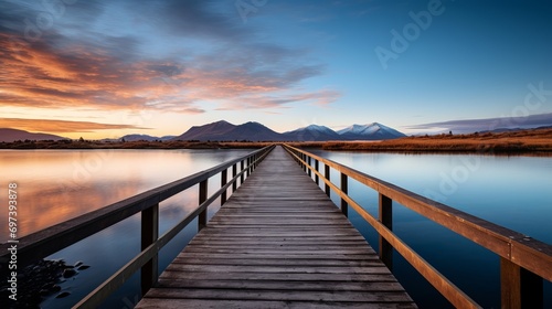 A vertical video showing a wooden passage over a small lake that is reflective and a mountain range on the horizon