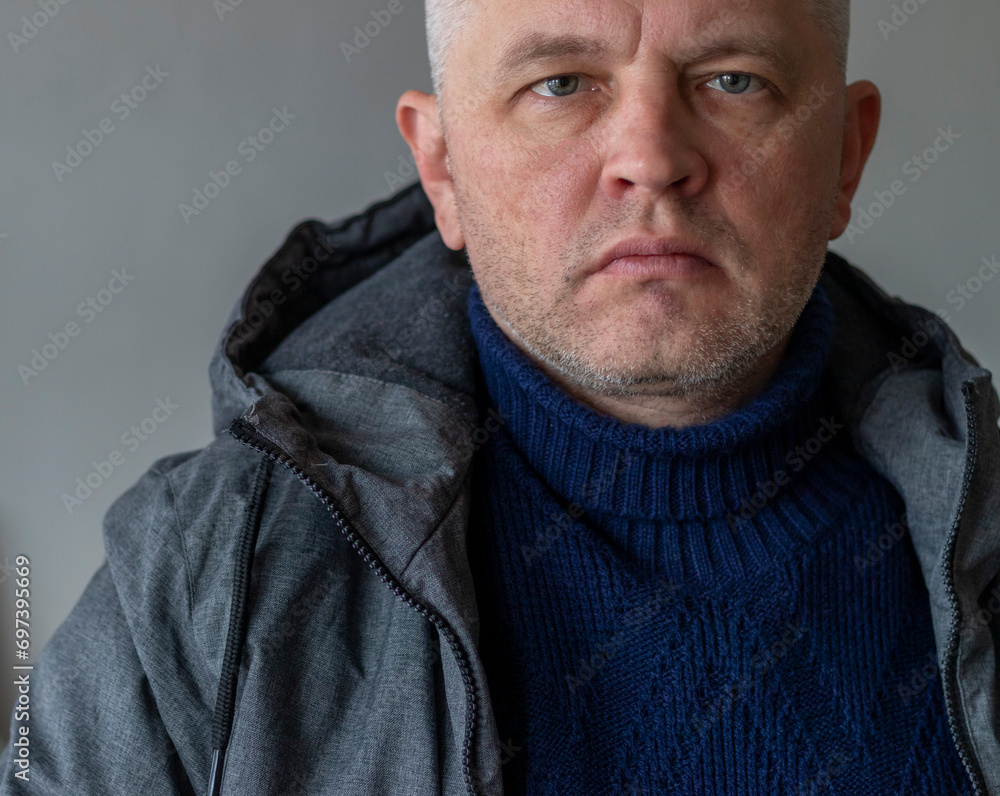 Obraz premium Portrait of the mid aged man with grey hair, wearing warm, dark blue sweater and grey coat. People