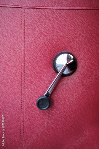 Chrome handle for opening a window on a red car door,