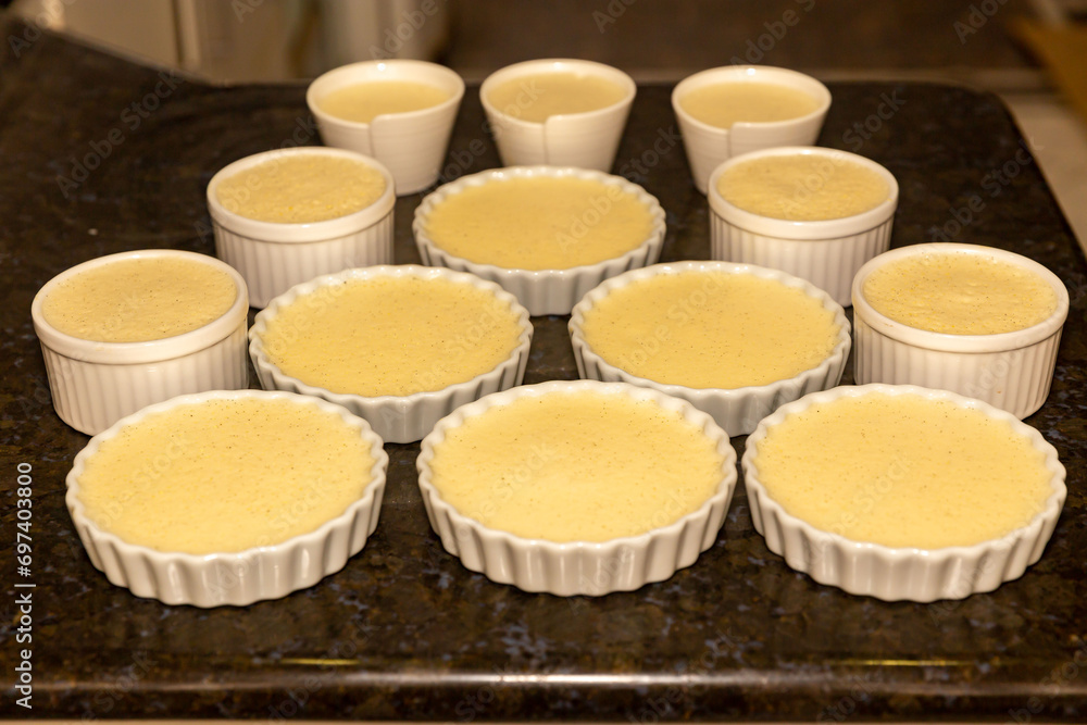 Creme brulee in white ramekins lined with white spoons on rustic background with shallow depth of field blur. Creme brulee in white ramekins lined with white spoons on rustic background with shallow depth of field blur.