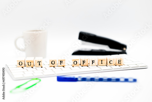 An office setting with wooden letter cubes illustrating an ‘Out of office’ message.