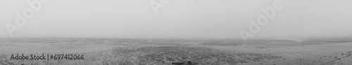 panoramic image of low tide in a river with silt on a very foggy day