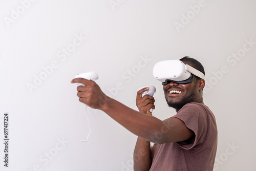 Excited Black Man wearing VR headset playing virtual reality game holding controllers. Man playing online games. VR gaming concept