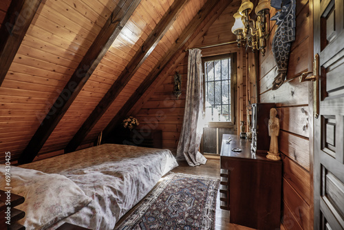 Photography A bedroom with a single bed in a log cabin with mansard roofs