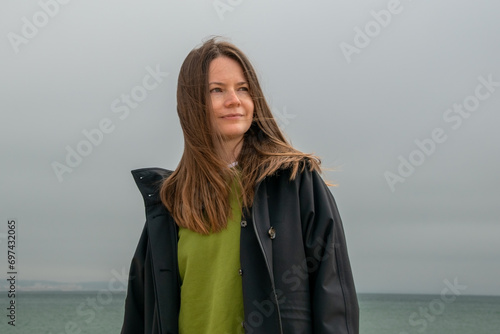 Portrait of a beautiful young woman in a raincoat on the beach