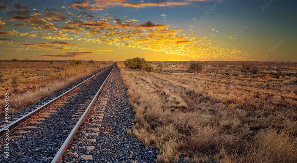 Peaceful sunrise over a vast open field with railroad tracks. space - obrazy, fototapety, plakaty 