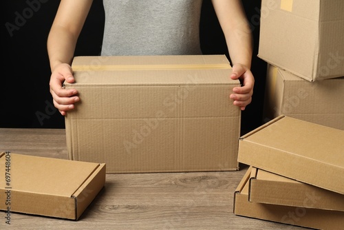 Packaging goods. Woman with cardboard boxes at wooden table, closeup © New Africa