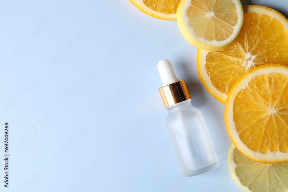 Bottle of cosmetic serum and sliced citrus fruits on light blue background, flat lay. Space for text Bottle of cosmetic serum and sliced citrus fruits on light blue background, flat lay. Space for text