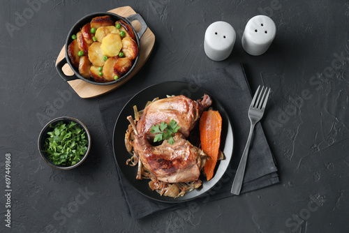 Tasty cooked rabbit meat with vegetables and potato served on black table, flat lay