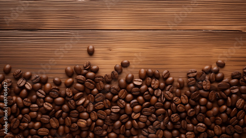 Dark brown roasted coffee beans beautifully scattered over an old brown wooden floor with copy space.