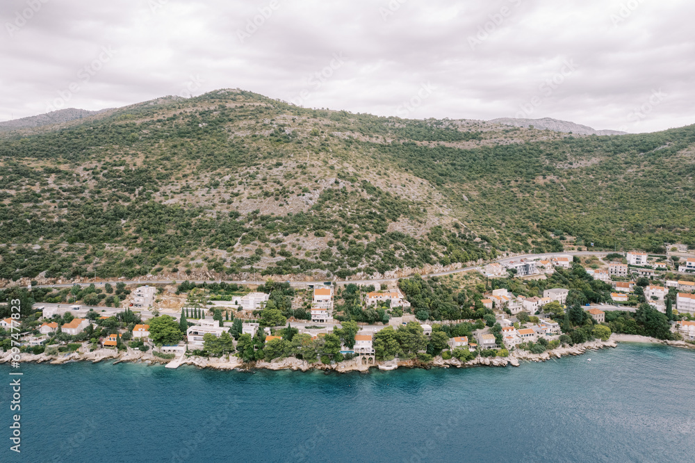 Small resort town on the shores of the Bay of Kotor at the foot of the mountains. Montenegro. Drone