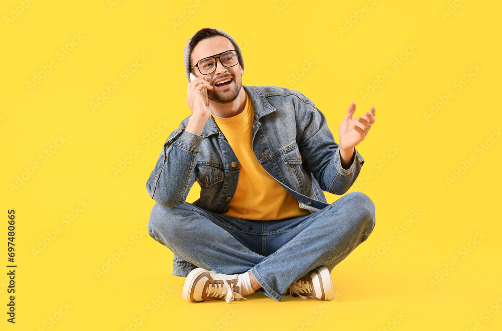Young man talking by mobile phone on yellow background Young man talking by mobile phone on yellow background