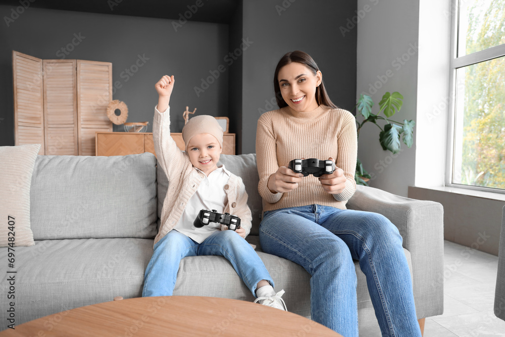 Little girl after chemotherapy with her mother playing video game at home Little girl after chemotherapy with her mother playing video game at home