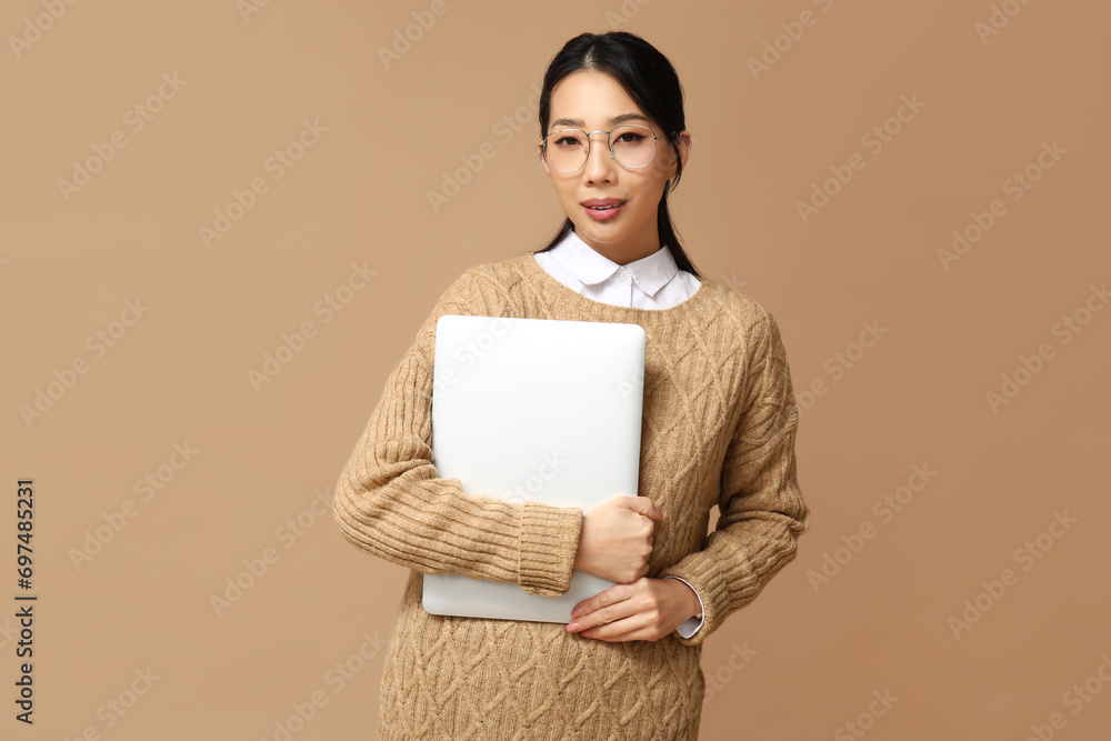 Portrait of young Asian businesswoman with modern laptop on beige background Portrait of young Asian businesswoman with modern laptop on beige background