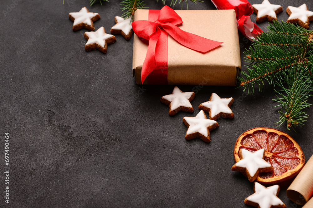 Composition with delicious stars shaped Christmas cookies, orange dried piece, gift box and fir tree branch on dark background, closeup Composition with delicious stars shaped Christmas cookies, orange dried piece, gift box and fir tree branch on dark background, closeup