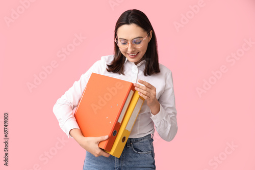 Young businesswoman with document folders on pink background © Pixel-Shot