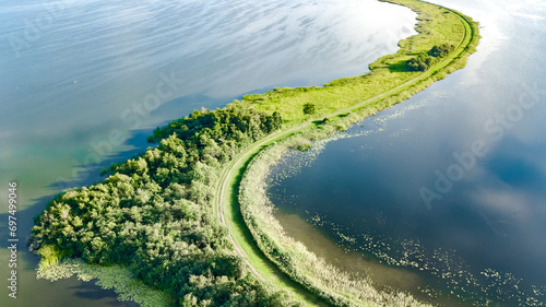 Aerial drone view of path on dam in polder water from above, landscape and nature of North Holland, Netherlands 