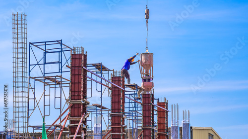 Tableau sur toile Two construction workers on scaffolding are pouring concrete from mixer concrete