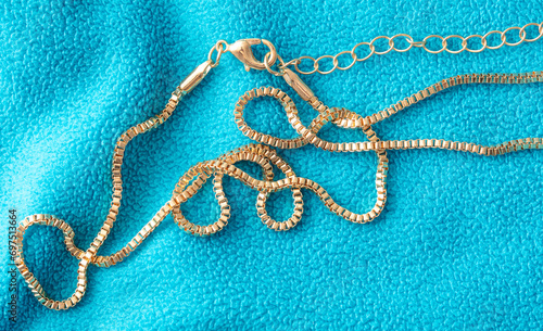 Gold chain on blue fabric. Close-up