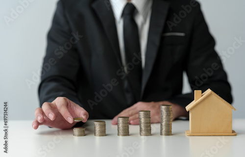 Businessman holds stacked coins to plan home purchase Concept of saving money for financial accounting Saving money for wealth Savings for future planning.
