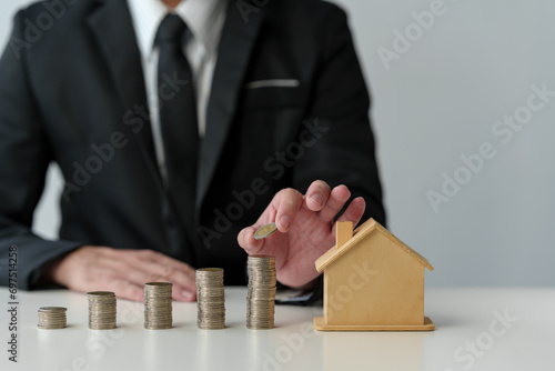 Businessman holds stacked coins to plan home purchase Concept of saving money for financial accounting Saving money for wealth Savings for future planning.