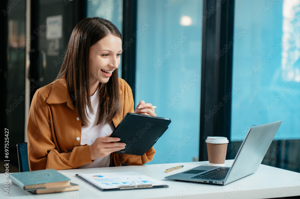 Business expert attractive smiling young woman typing laptop and holding digital tablet Business expert attractive smiling young woman typing laptop and holding digital tablet