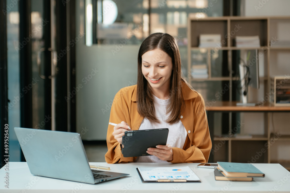 Business expert attractive smiling young woman typing laptop and holding digital tablet Business expert attractive smiling young woman typing laptop and holding digital tablet