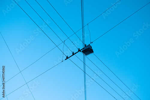 tangled wires with a lamp against the background of a bright blue sky