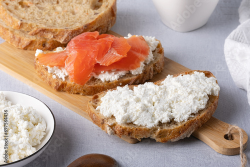 Sandwich with salted salmon and cottage cheese on a wooden table