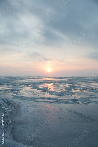 Large pieces of ice near the river bank at sunset