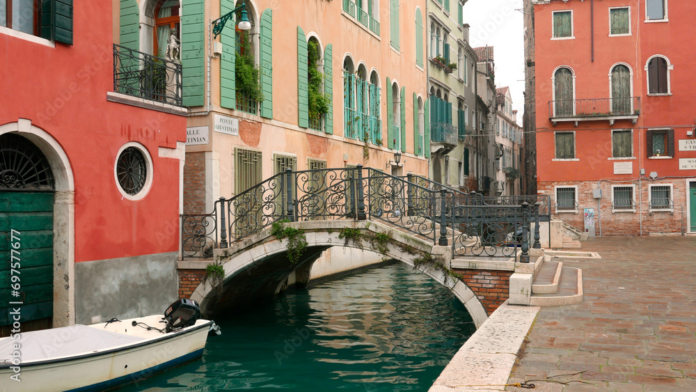 Venice picturesque small bridge 'Ponte Giustinian' and buildings with attractive complementary red and green colors.