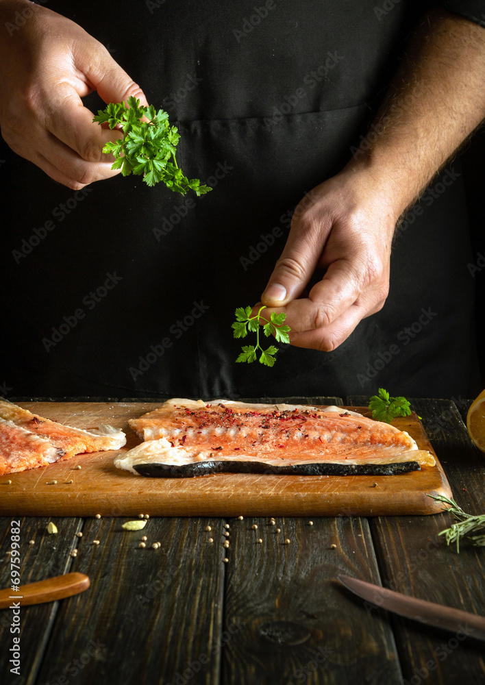 Fragrant parsley for fish in the hands of a cook. The process of preparing salmon fish by the hands of a chef in a hotel kitchen.