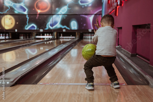 little child boy playing bowling in a club