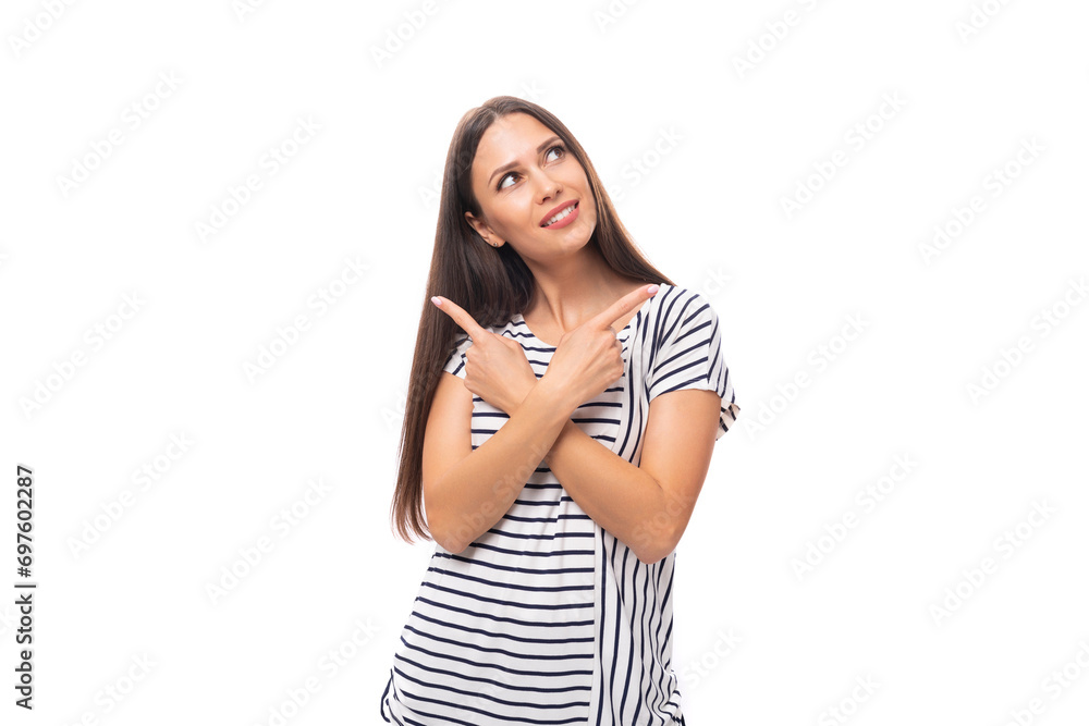 young pretty caucasian brunette woman in a striped t-shirt points her hand to the side on a white background with copy space young pretty caucasian brunette woman in a striped t-shirt points her hand to the side on a white background with copy space