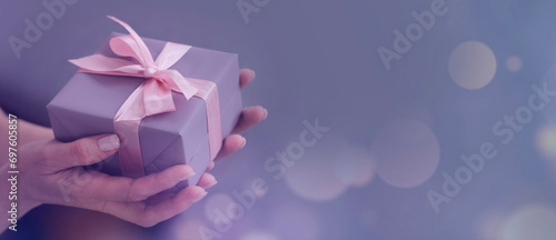  photo of hands holding craft paper giftbox with ribbon bow. banner. Birthday, Mother's Day, Father's Day, Valentine's Day.