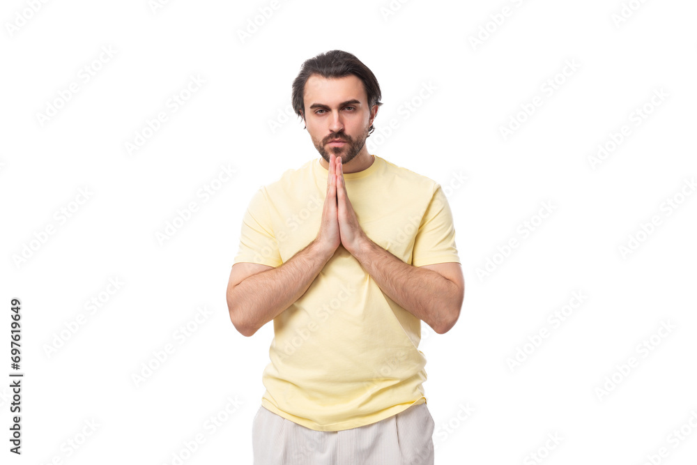 caucasian smart brutal charming guy with a beard dressed in a summer t-shirt folded his hands together caucasian smart brutal charming guy with a beard dressed in a summer t-shirt folded his hands together