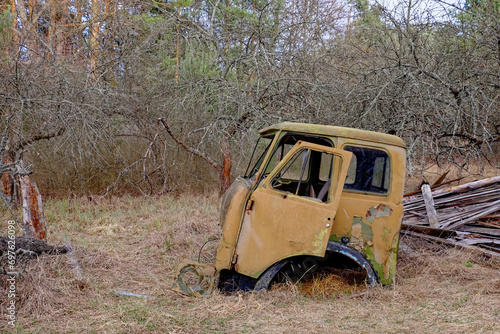 A rusted, abandoned car in a wooded area.