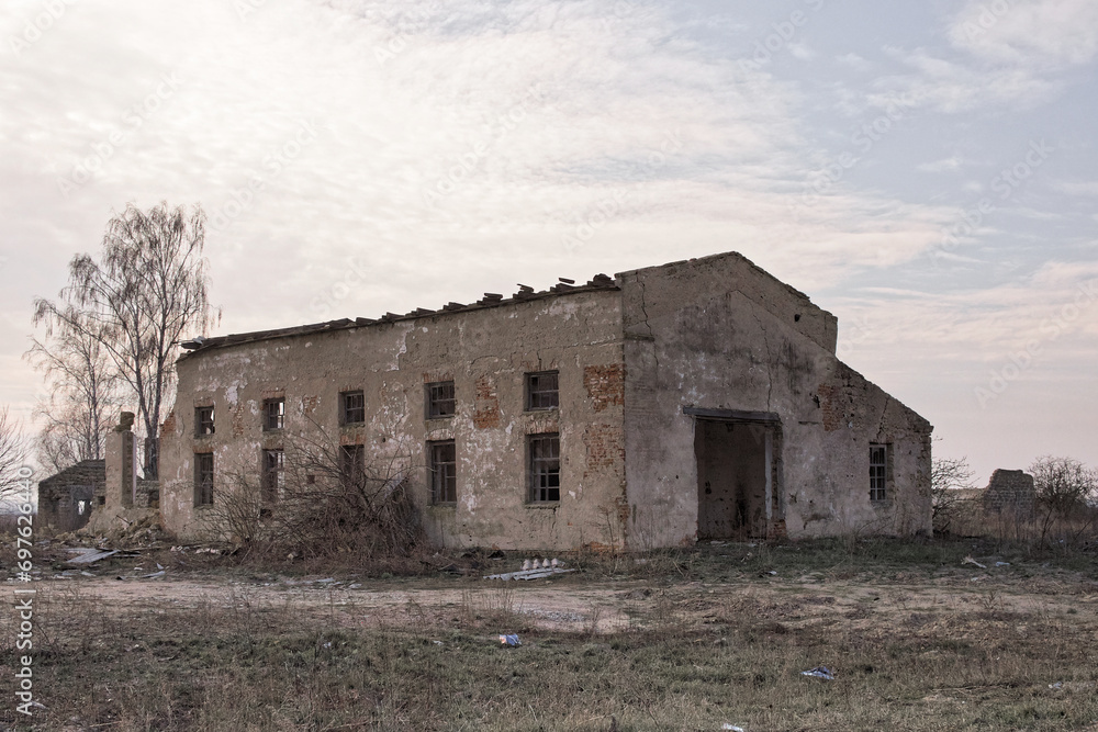 An abandoned structure surrounded by overgrown grass and bare trees. An abandoned structure surrounded by overgrown grass and bare trees.