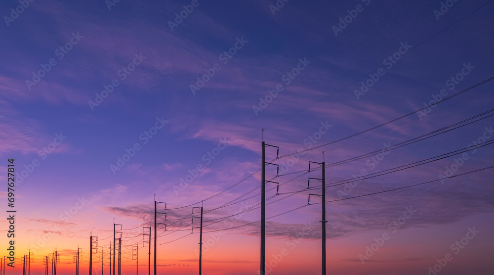 Silhouette two rows of electric poles with cable lines against colorful dramatic twilight sky background, low angle view with copy space
