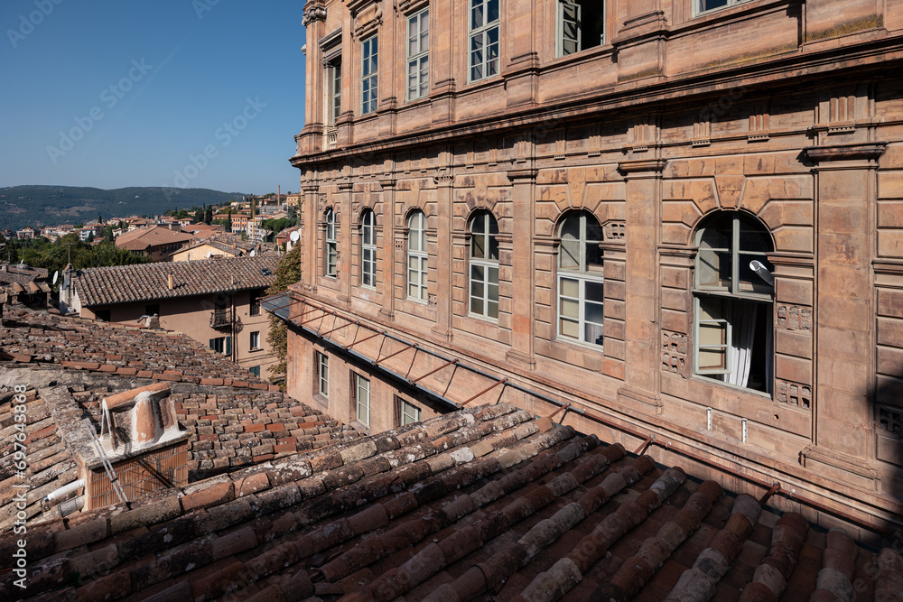 Medieval Italian town with brick houses and tiled roofs and distant hills at sunny day, Perugia, Italy