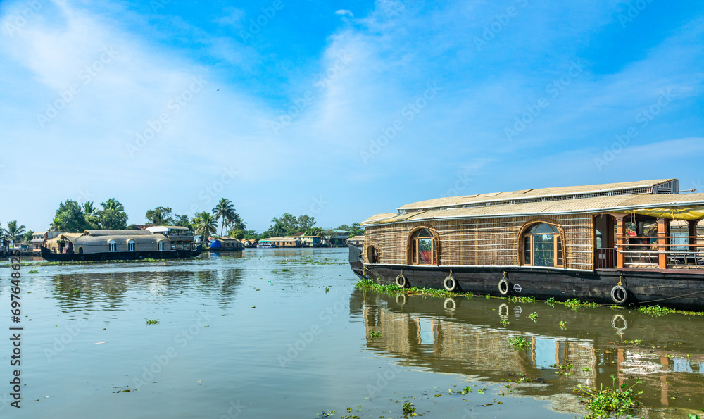 Indian traditional houseboats floating on Pamba river, with palms at the coastline, Alappuzha, Kerala, South India
